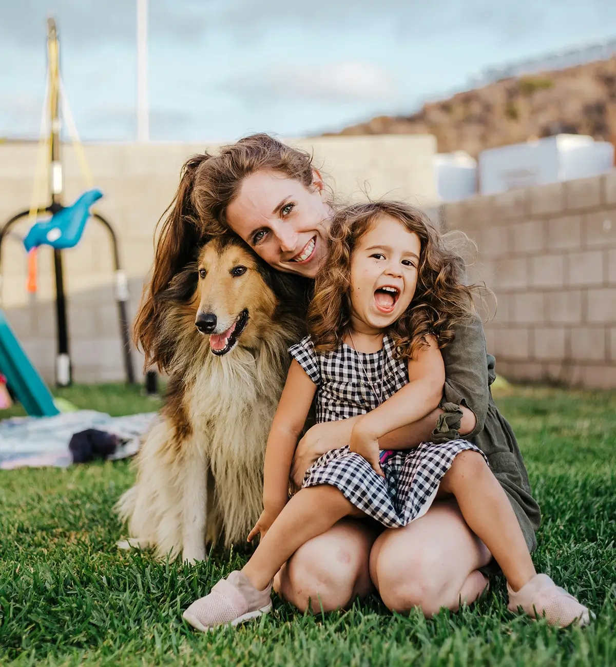 A mother and daughter hugging and smiling with their dog